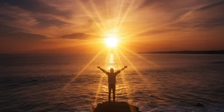 A person with arms outstretched towards a sunrise or sunset over the ocean For the page: Influencer 2. Use realistic, professional photography. Match the compos